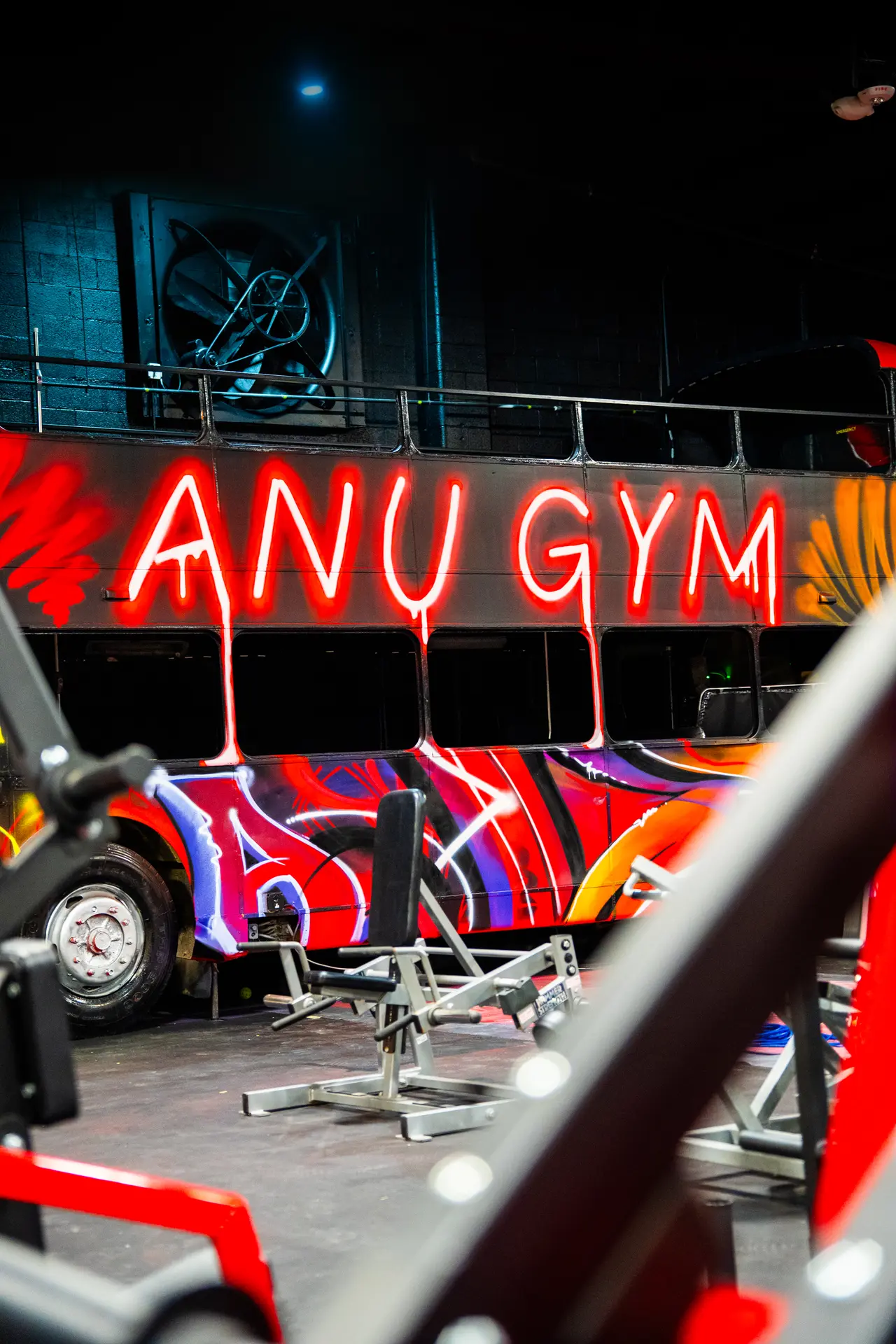 Custom painted double-decker bus inside Anu Gym with neon artwork